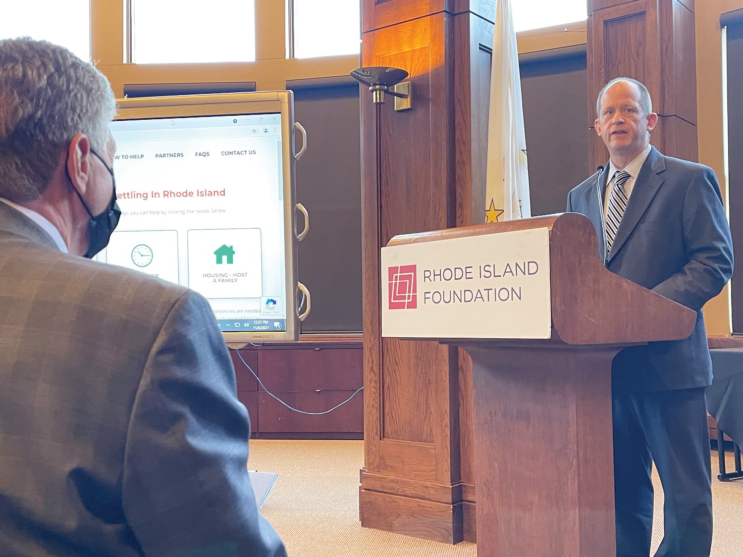 Gov. Dan McKee looks on as Secretary for Catholic Charities and Social Ministry James Jahnz speaks from the podium about how the Diocese of Providence will help to resettle Afghan evacuees in Rhode Island.